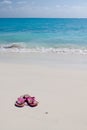 Pair of colored sandals on a white sand beach Royalty Free Stock Photo