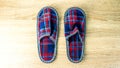 A pair of colorful comfortable, cushioned, checkered disposable slippers are on the wooden floor. Close-up