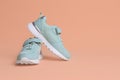 Pair of comfortable sports shoes on pale coral background. Space for text