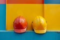 Pair of construction worker safety hard hats in a bright multi-colored room. Two colorful industrial engineer protective Royalty Free Stock Photo