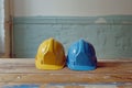 Pair of construction worker safety hard hats on a table in a bright room. Two colorful industrial engineer protective Royalty Free Stock Photo