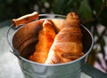 Pair of croissants in a tin bucket lit by strong morning sun li Royalty Free Stock Photo