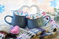 A pair of cups with a drink decorated with meringues and marshmallows, Christmas decor, hearts, knitted scarf on the windowsill