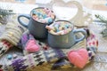 A pair of cups with a drink decorated with meringues and marshmallows, Christmas decor, hearts, knitted scarf on the windowsill
