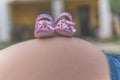 Pair of cute, pink baby shoes with brown dots on the pregnant mother' belly Royalty Free Stock Photo