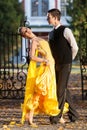 Pair of dancers dancing in the woods. Man with suit, woman in yellow long dress middle of the palace park in autumn. Dry fallen c Royalty Free Stock Photo