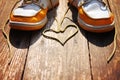 A pair of deck shoes on a nice wooden porch with the laces in a heart shape