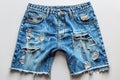 A pair of denim shorts, heavily distressed with holes, laid flat on a surface