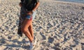 A pair of denim shorts, sneakers and legs and thighs on a beach sunset Royalty Free Stock Photo