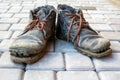 A pair of dirty boots. Old worn dark blue leather shoes with variegated brown laces. Background from gray pavers. The concept of Royalty Free Stock Photo