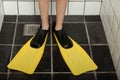 Pair of diving flippers on feet in shower stall