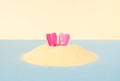 A pair of diving pink fins pokes out of the sand on blue and yellow pastel background. Creative idea of summer swimming undersea Royalty Free Stock Photo