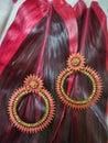 Pair of ear rings in pink colour on two red leafs