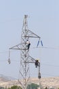 Workers over a high tension tower making reparations. Royalty Free Stock Photo