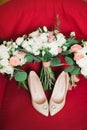 Pair of elegant and stylish bridal shoes with wedding rings and a bouquet of roses and other flowers Royalty Free Stock Photo