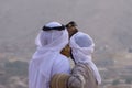 A pair of Emirati falconers hold a peregrine falcon Falco peregrinus in the United Arab Emirates UAE a culture and tradition