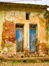 Pair of faded blue doors behind locked grate on brick wall with broken plaster Royalty Free Stock Photo