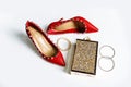 Pair of red high-heeled shoes with pointed toes, decorated with metal blue inserts and metal clutch with sparcles on a white Royalty Free Stock Photo