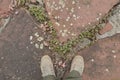 Pair of feet in canvas shoes on aged stones sidewalk