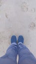 a pair of feet of a person wearing shoes on the beach sand