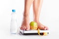 A pair of female feet standing on a bathroom scale with green ap Royalty Free Stock Photo