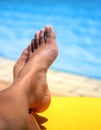 Pair of feminine feet resting on a sun lounger