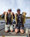 Pair of Fishermen Holding Largemouth Bass While Fishing in a Boat