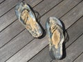 Pair of flip flops covered with sand on a wooden surface Royalty Free Stock Photo