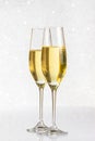 A pair of flutes of golden champagne on silver bokeh