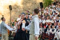 A pair of folk dancers in front of the folk choir singers