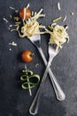 Pair of forks with rolled spaghetti, cherry tomatoes and zucchini