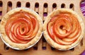 Pair of Homemade Rose Shaped Apple Tartlets on Wooden Breadboard