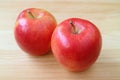 Pair of fresh vibrant red apples on light brown wooden table