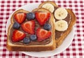 Pair of Fruit and Chocolate Hazelnet Spread Toast on a Red and White Plaid Tablecloth Royalty Free Stock Photo