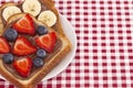 Pair of Fruit and Chocolate Hazelnet Spread Toast on a Red and White Plaid Tablecloth Royalty Free Stock Photo