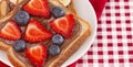 Pair of Fruit and Chocolate Hazelnet Spread Toast on a Red and White Plaid Tablecloth Royalty Free Stock Photo