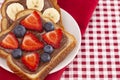 Pair of Fruit and Chocolate Hazelnet Spread Toast on a Red and White Plaid Tablecloth Royalty Free Stock Photo