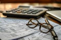 A pair of glasses is placed on top of a table alongside a calculator, Tax preparation tools and documents, AI Generated Royalty Free Stock Photo