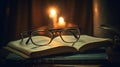 a pair of glasses sitting on top of a book next to a lit candle in a dark room with curtains behind it and a book on a table Royalty Free Stock Photo