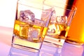 A pair of glasses of whiskey with ice on disco violet light Royalty Free Stock Photo