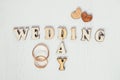 Pair gold rings with two wooden hearts and inscription wedding day on white background