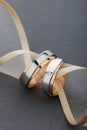Pair of gold wedding rings on gray background with ribbon Royalty Free Stock Photo