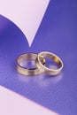 Pair of gold wedding rings on purple and pink background Royalty Free Stock Photo