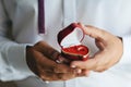 Pair of gold wedding rings in red heart-shaped box in hands of groom on wedding day horizontal shot Royalty Free Stock Photo