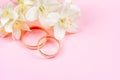 Pair of gold wedding rings and white Jasmine flowers on pink background Royalty Free Stock Photo