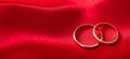 Two golden wedding rings on red satin background, banner, copy space Royalty Free Stock Photo