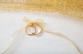 Two golden wedding rings tied with a golden ribbon on white wooden background Royalty Free Stock Photo