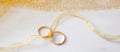 Two golden wedding rings tied with a golden ribbon on white wooden background Royalty Free Stock Photo