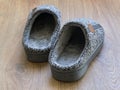 Pair of a gray mens house slippers on a brown wooden floor. Cozy, warm and comfortable domestic shoes Royalty Free Stock Photo