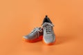 Pair of gray sneakers over orange background